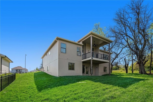 rear view of property featuring fence, a lawn, a balcony, and ceiling fan