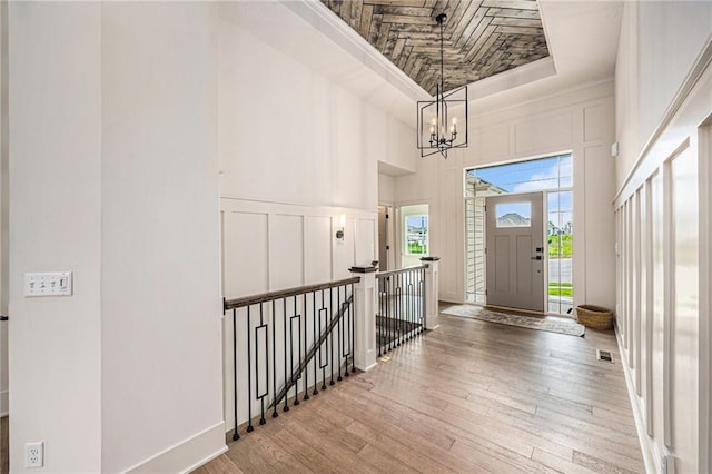 entrance foyer with visible vents, a decorative wall, a towering ceiling, a chandelier, and hardwood / wood-style flooring