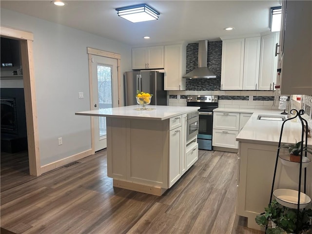 kitchen featuring dark hardwood / wood-style flooring, a kitchen island, stainless steel appliances, backsplash, and wall chimney exhaust hood