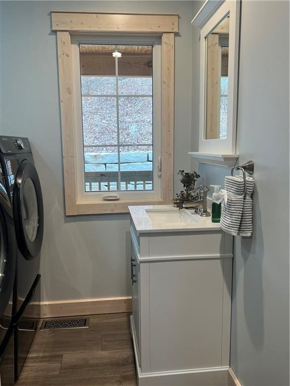 bathroom with washer and dryer, vanity with extensive cabinet space, hardwood / wood-style floors, and a wealth of natural light