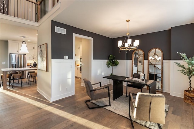 dining room featuring a decorative wall, wainscoting, visible vents, a notable chandelier, and dark wood-type flooring