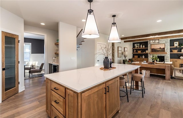 kitchen featuring a stone fireplace, dark wood-type flooring, hanging light fixtures, and a kitchen island