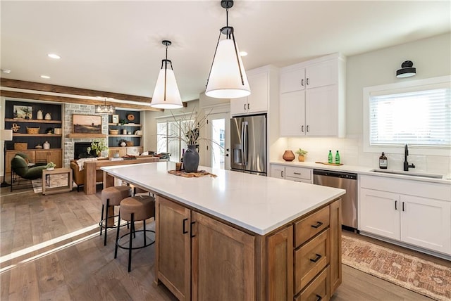 kitchen with stainless steel appliances, a kitchen island, white cabinets, dark wood-style flooring, and a sink
