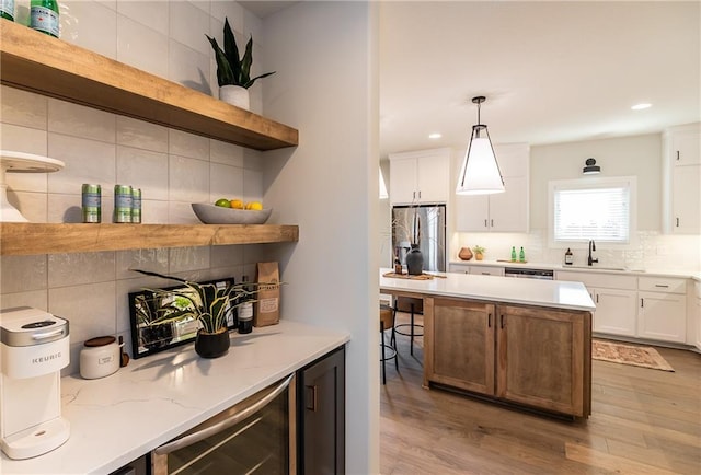 kitchen featuring a sink, decorative backsplash, open shelves, appliances with stainless steel finishes, and beverage cooler