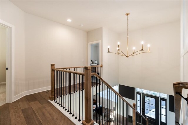 stairway with recessed lighting, a notable chandelier, wood finished floors, and baseboards