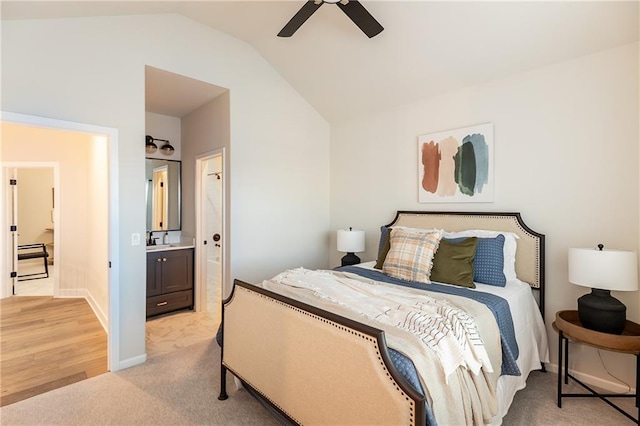 bedroom featuring a sink, light colored carpet, ceiling fan, baseboards, and vaulted ceiling