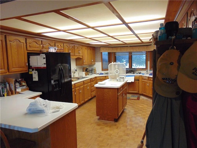 kitchen with light parquet floors, a kitchen island, and black fridge