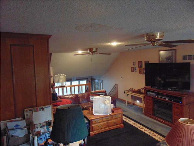 living room with ceiling fan, lofted ceiling, dark colored carpet, and a textured ceiling