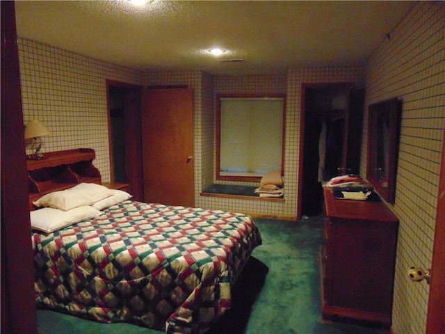 bedroom featuring a textured ceiling and dark colored carpet