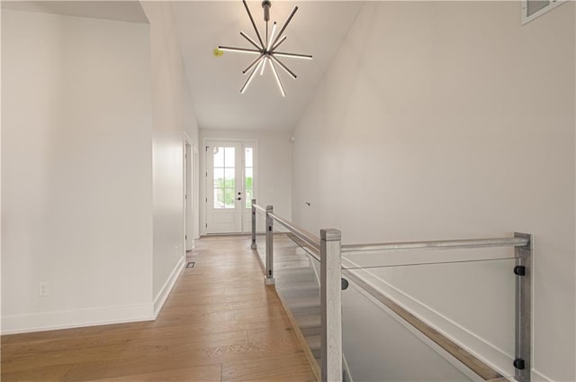 7551 NW Gower Ave, Kansas City, MO 64151 - hall with light wood-type flooring, an upstairs landing, baseboards, visible vents, and a notable chandelier