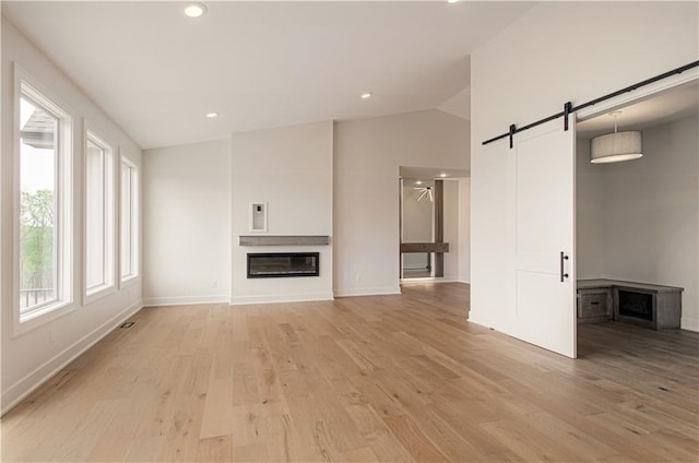 7551 NW Gower Ave, Kansas City, MO 64151 - unfurnished living room featuring a barn door, recessed lighting, light wood-style flooring, and baseboards