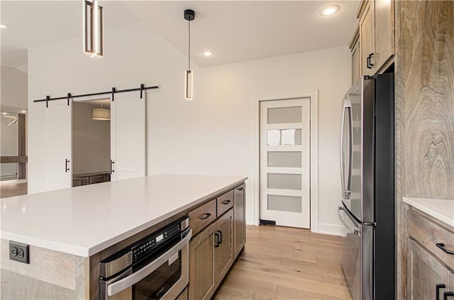 7551 NW Gower Ave, Kansas City, MO 64151 - kitchen featuring recessed lighting, a barn door, stainless steel appliances, decorative light fixtures, and light wood-style flooring