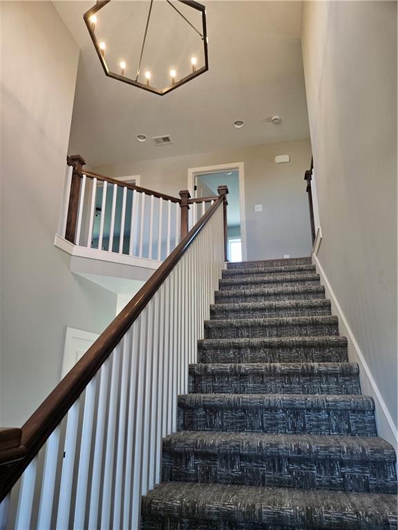 stairs featuring a chandelier