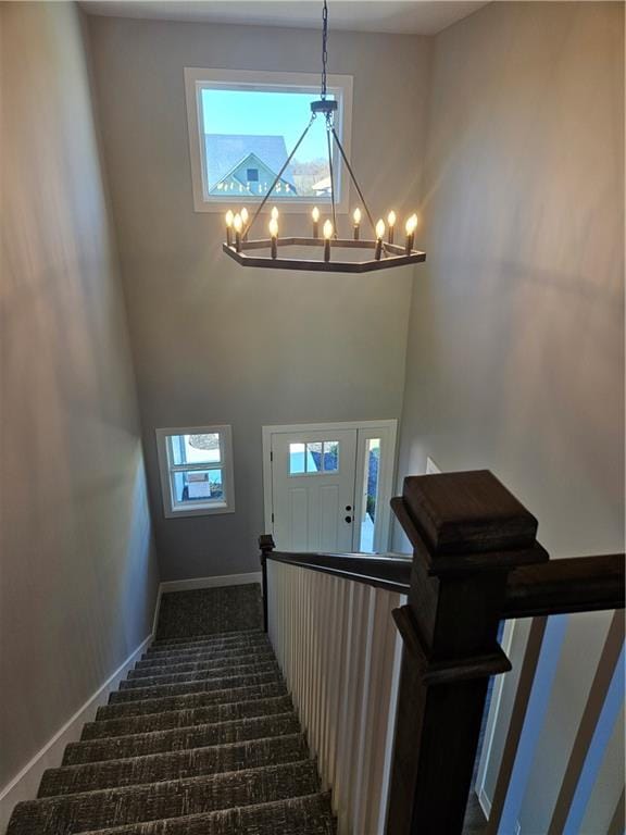 staircase featuring a chandelier, carpet, and a high ceiling