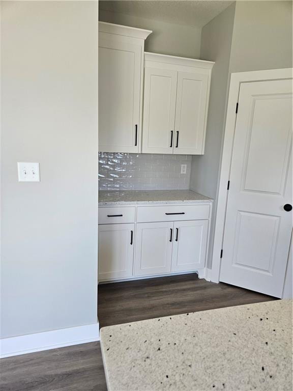 kitchen with decorative backsplash, white cabinetry, dark hardwood / wood-style flooring, and light stone counters