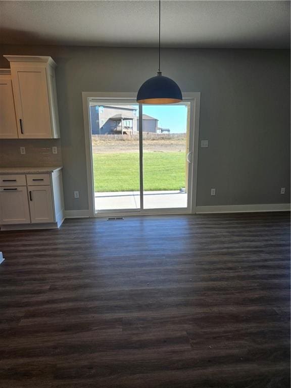 unfurnished dining area featuring dark wood-type flooring