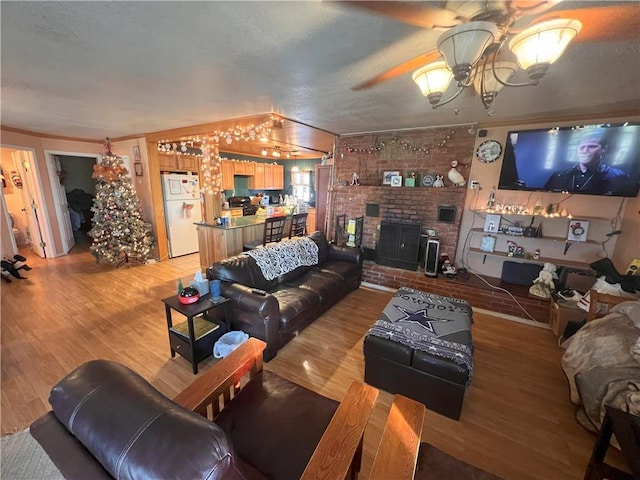 living room featuring a brick fireplace, hardwood / wood-style floors, and ceiling fan