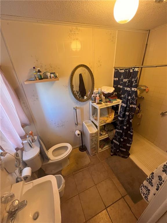 bathroom with sink, toilet, tile patterned floors, and a textured ceiling