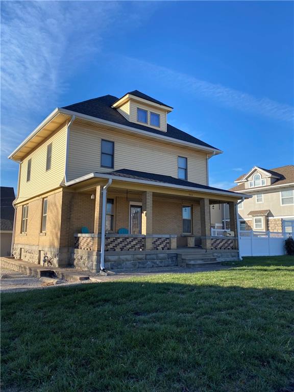 rear view of house featuring a yard and covered porch