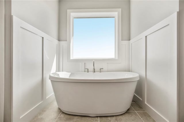 bathroom with tile patterned floors, plenty of natural light, and a washtub