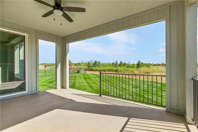 unfurnished sunroom featuring a rural view and ceiling fan