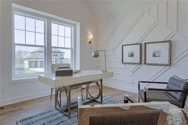 home office featuring a healthy amount of sunlight, lofted ceiling, and hardwood / wood-style floors