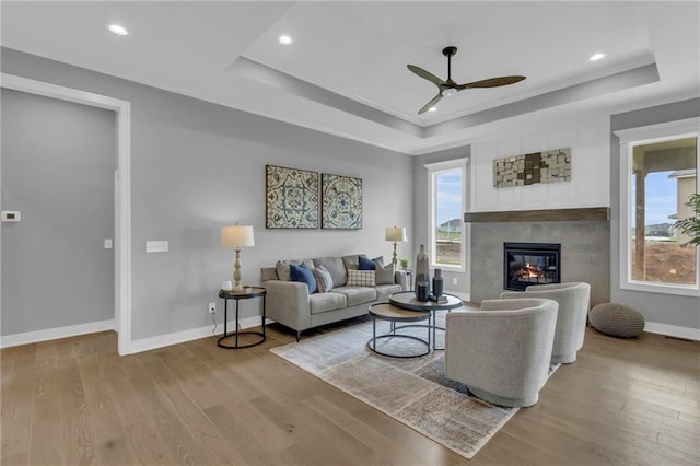 16879 S Cardinal St, Olathe, KS 66062 - living area with a tray ceiling, a ceiling fan, light wood-style floors, a fireplace, and baseboards