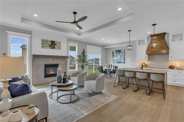16879 S Cardinal St, Olathe, KS 66062 - living area with a raised ceiling, a ceiling fan, light wood-type flooring, a tile fireplace, and recessed lighting