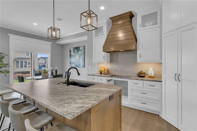 16879 S Cardinal St, Olathe, KS 66062 - kitchen with a sink, custom exhaust hood, backsplash, a kitchen bar, and white cabinets