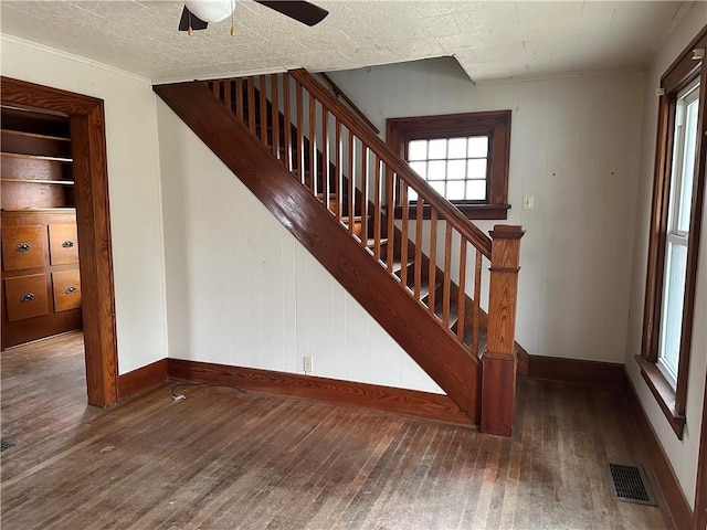 stairway with visible vents, a textured ceiling, baseboards, and wood finished floors