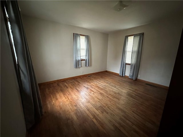 spare room with visible vents, dark wood finished floors, and baseboards