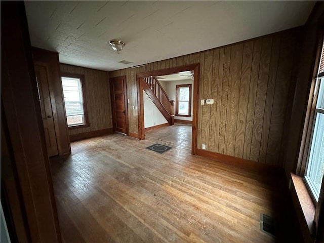 spare room with light wood finished floors, plenty of natural light, stairs, and visible vents