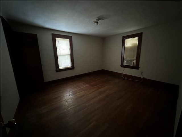 empty room featuring dark wood-style flooring, cooling unit, and baseboards