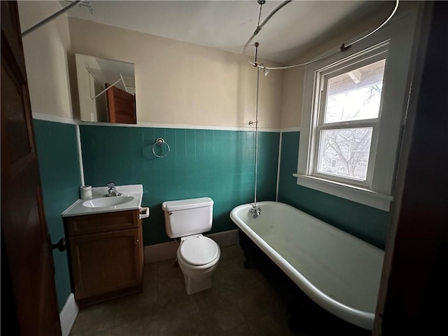 bathroom featuring toilet, a combined bath / shower with freestanding tub, wainscoting, and vanity