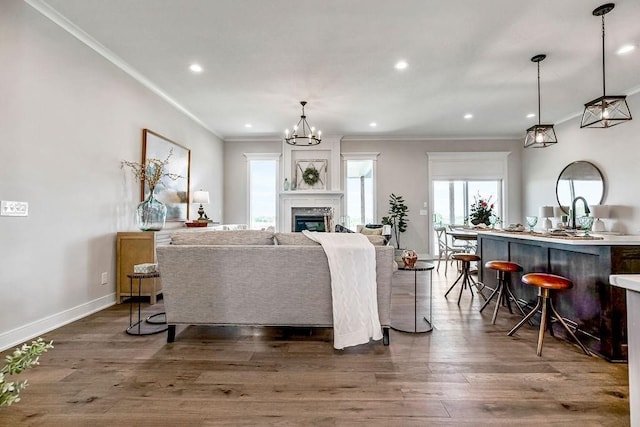 living room with crown molding, dark hardwood / wood-style flooring, a notable chandelier, and sink