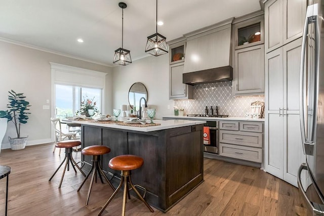 kitchen with gray cabinets, an island with sink, pendant lighting, and custom exhaust hood