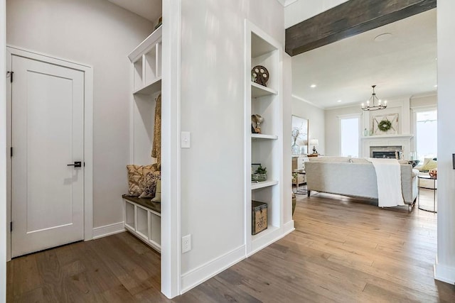 corridor with built in features, hardwood / wood-style floors, and a notable chandelier