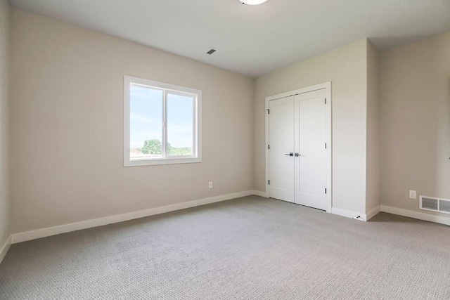 unfurnished bedroom with light carpet and a closet