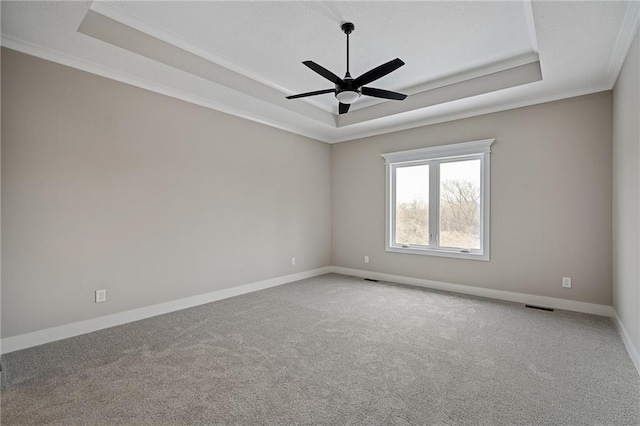 carpeted empty room featuring a tray ceiling, ceiling fan, and crown molding