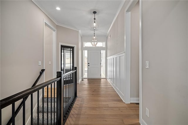 hallway with ornamental molding and light hardwood / wood-style floors