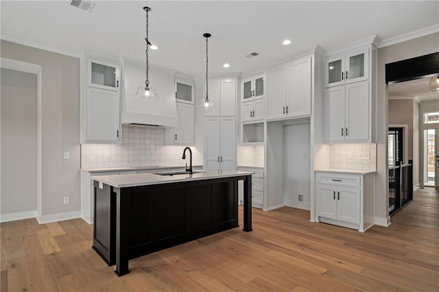 kitchen with sink, white cabinets, a kitchen island with sink, and hanging light fixtures