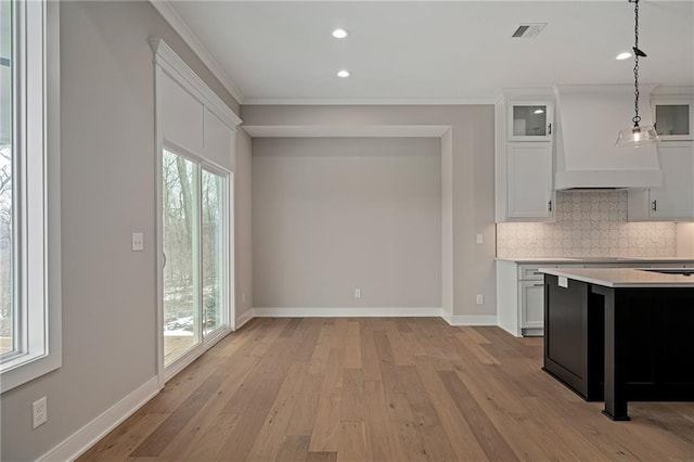 kitchen featuring light hardwood / wood-style flooring, white cabinetry, a healthy amount of sunlight, hanging light fixtures, and tasteful backsplash