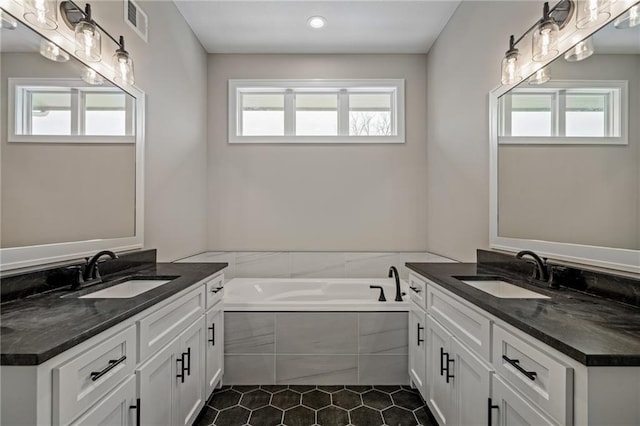 bathroom featuring vanity, tile patterned floors, and tiled bath