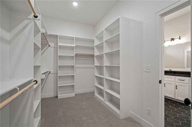 spacious closet featuring sink and dark colored carpet