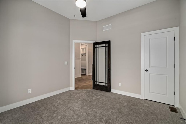 unfurnished bedroom with ceiling fan and dark colored carpet