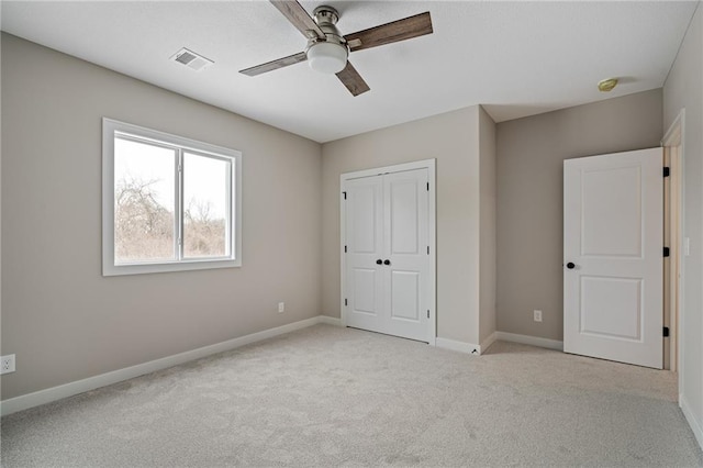 unfurnished bedroom with a closet, light colored carpet, and ceiling fan