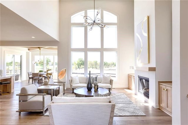 living room with light hardwood / wood-style flooring, a chandelier, and a high ceiling