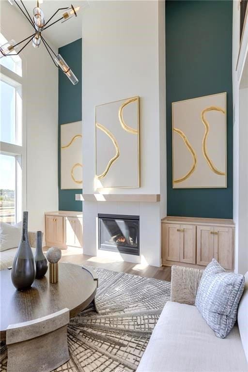 2461 W 176th St, Overland Park, KS 66085 - living area featuring a chandelier, a glass covered fireplace, a high ceiling, and wood finished floors