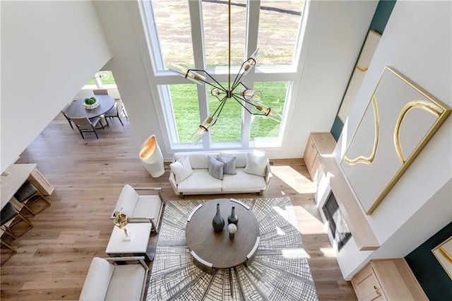 living room with light wood-type flooring, a chandelier, and a towering ceiling