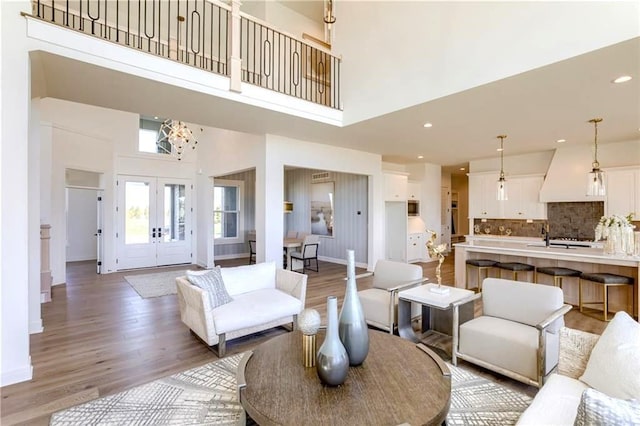 living room featuring french doors, a high ceiling, and light hardwood / wood-style floors